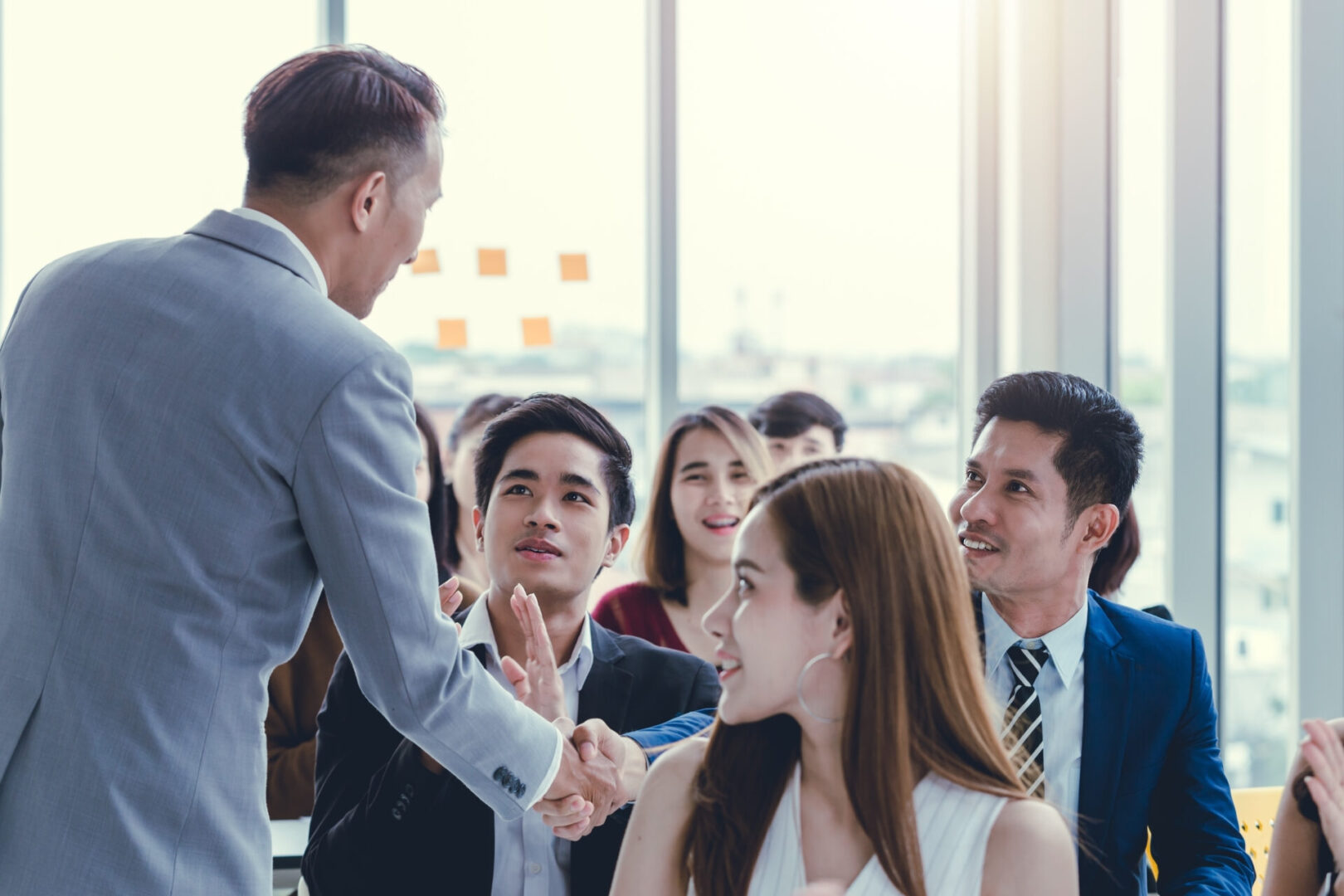 A man shaking hands with another person in front of other people.