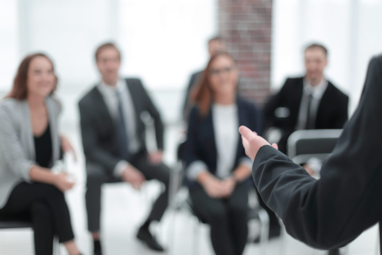 A group of people sitting in chairs and one person is holding his hand out to the audience.